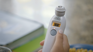 A hand holding the Exergen TAT-2000C Temporal Artery Thermometer